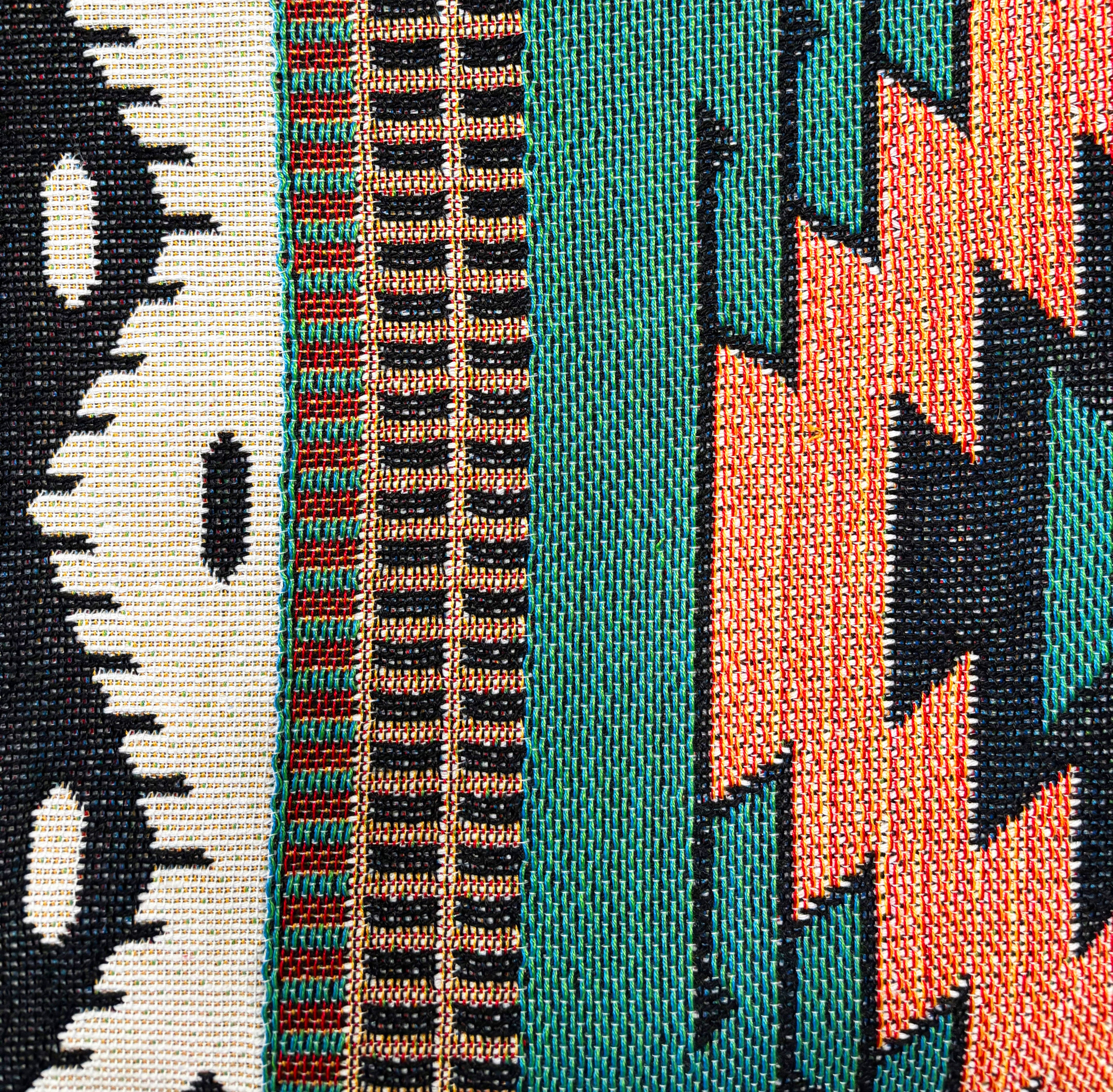 Close-up of a woven fabric with geometric patterns in black, white, green, and orange.