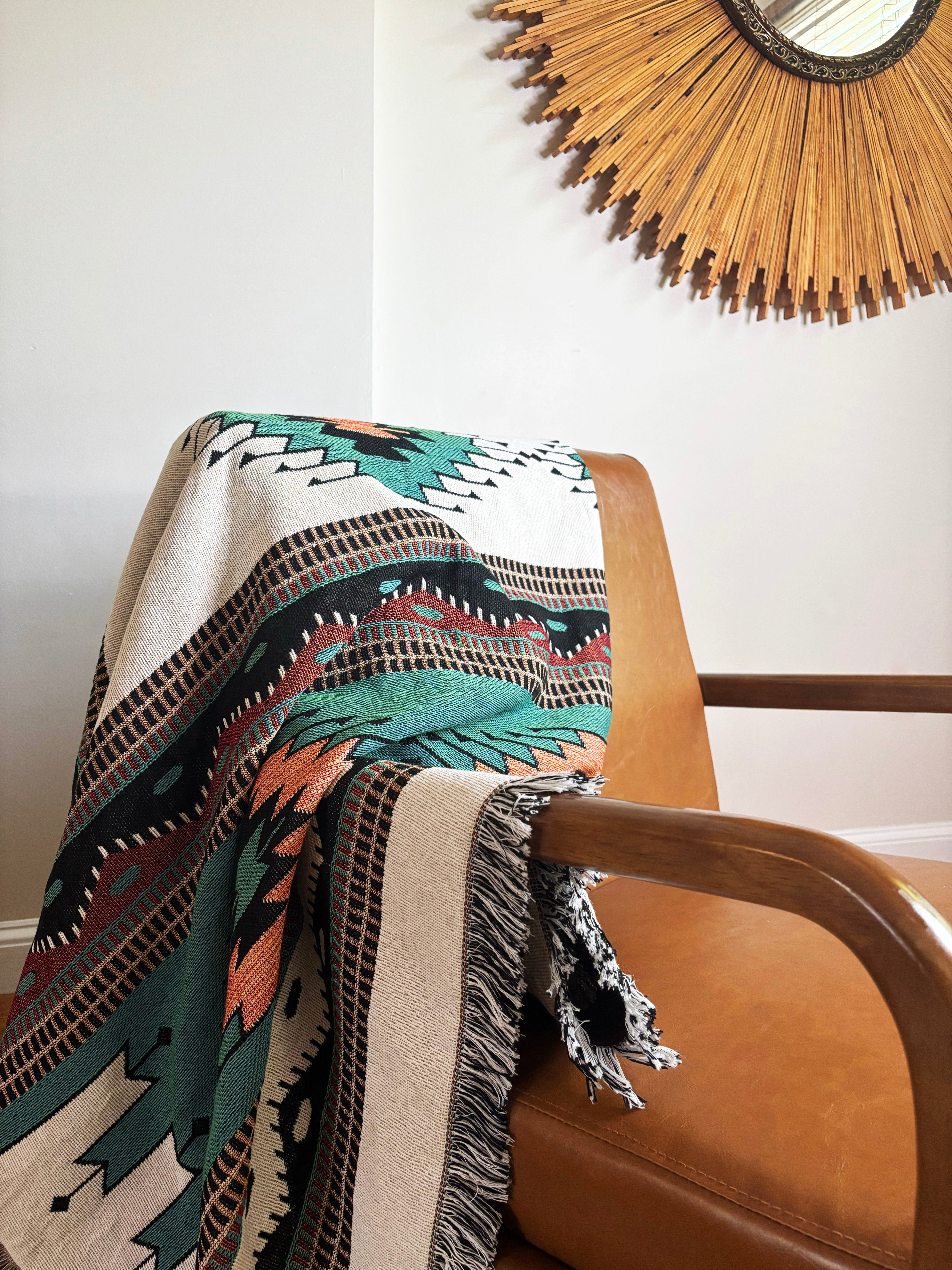 Patterned blanket draped over a chair with a decorative mirror in the background