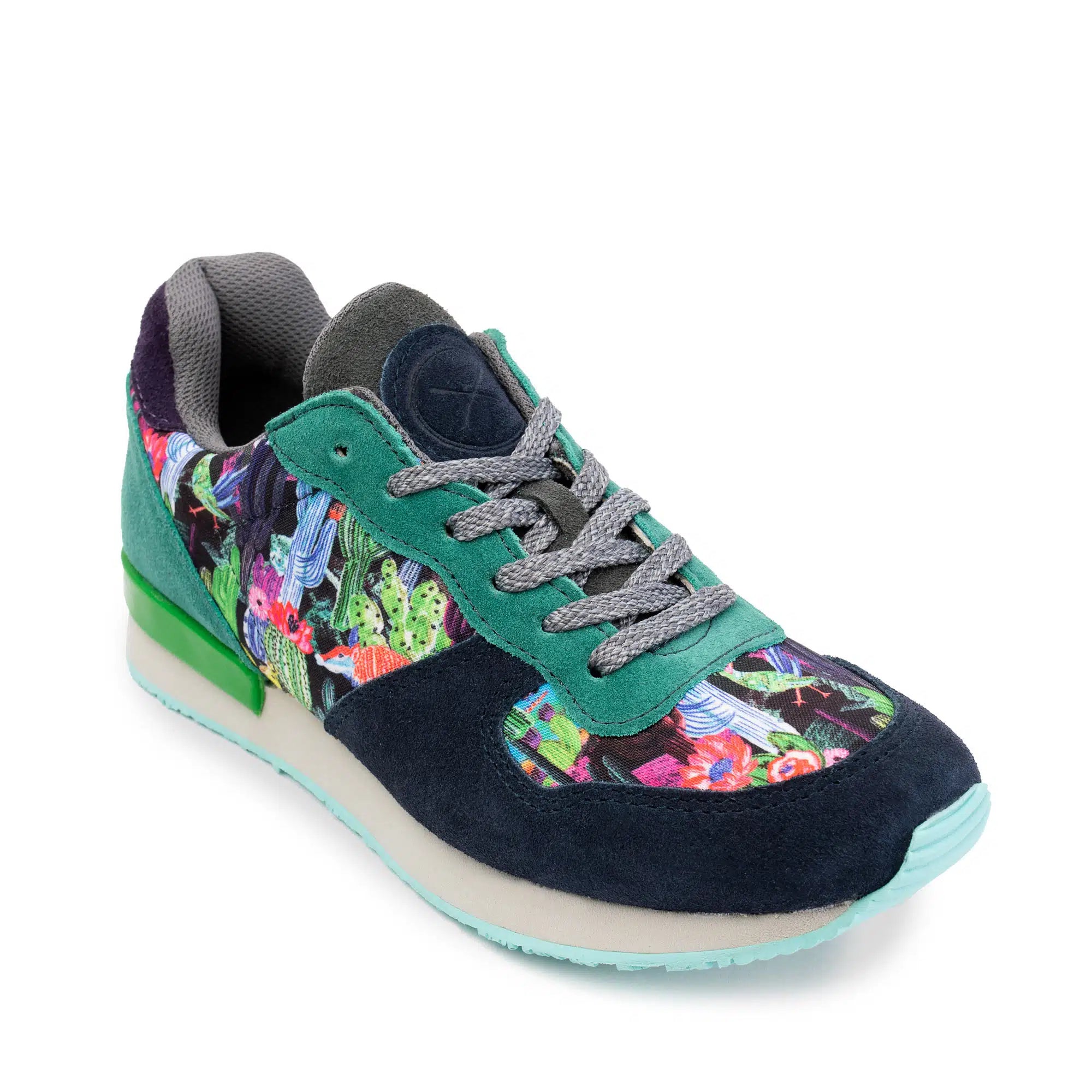 A low-top sneaker with a dark navy suede toe and heel, teal green suede overlays, a colorful floral and botanical print side panel, gray laces, and a light blue-tipped outsole on a white background.