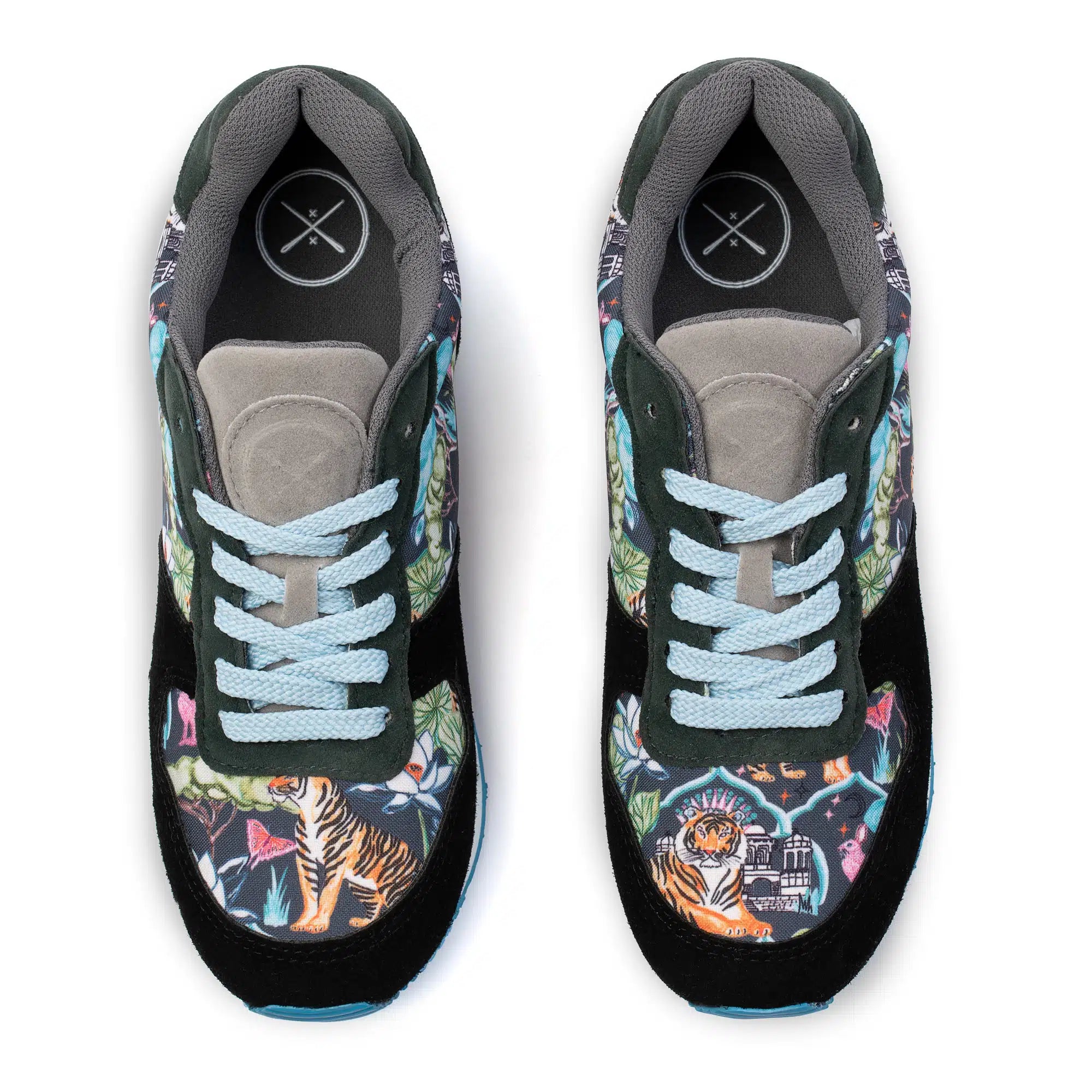 A pair of low-top sneakers shown from a top-down view on a white background. The shoes feature a dark green and black base with a vibrant multicolor tropical print on the toe boxes, light blue laces, and a gray padded collar.