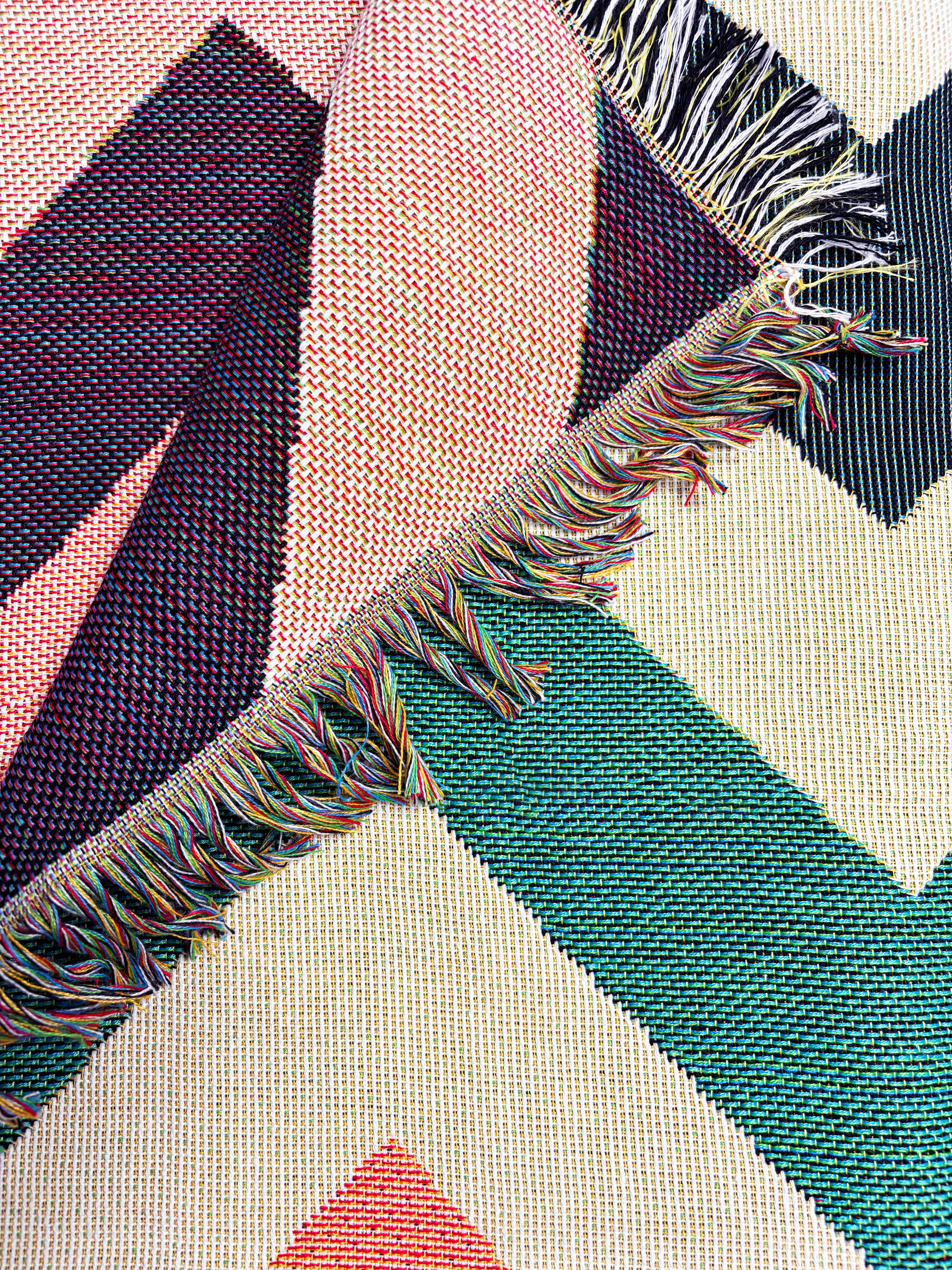 Close-up of a geometric patterned fabric with colorful fringes.