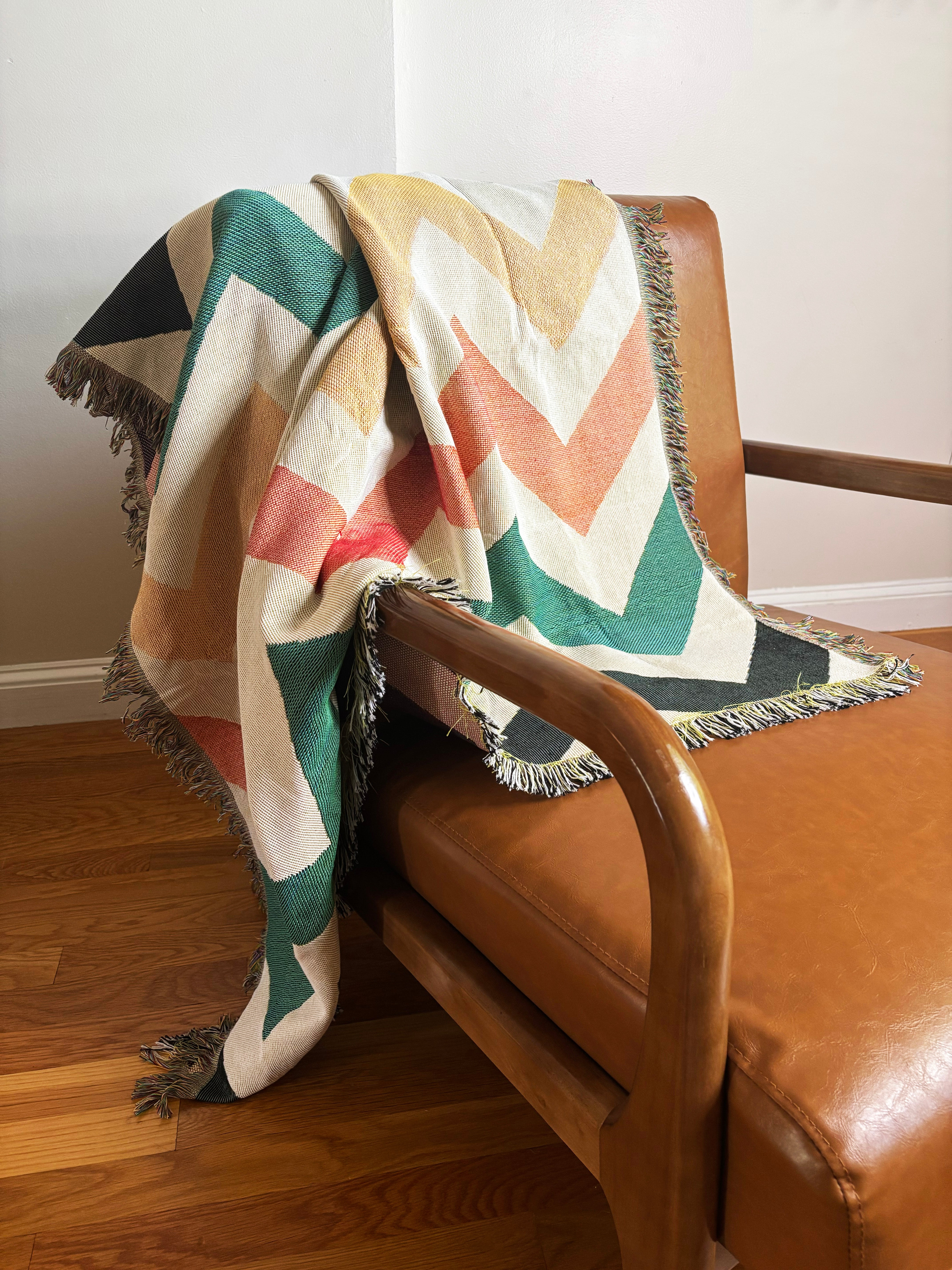 Colorful chevron-patterned blanket draped over a brown leather chair.