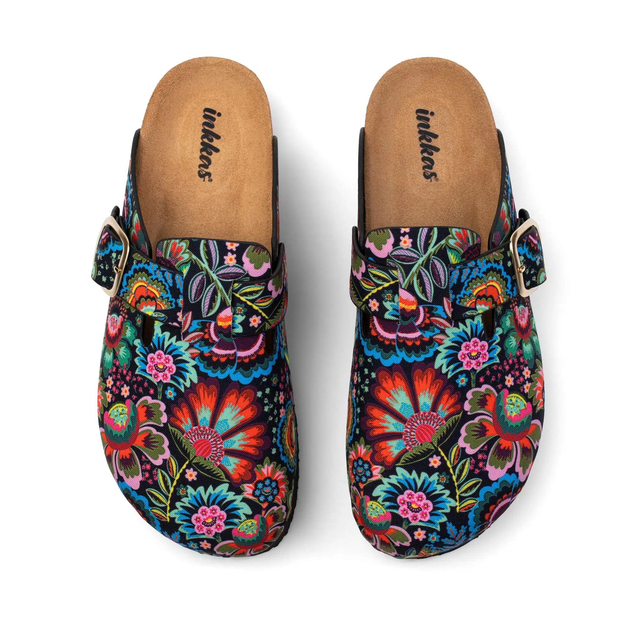 A pair of clog-style mule shoes with a vibrant, multicolored floral print on a black background, featuring a brown insole and a small gold buckle on the side, shown from a top-down view on a white background.