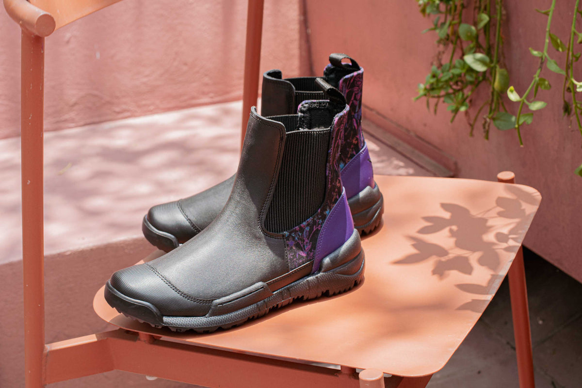 An Inkkas Chelsea boot with a purple textile panel on a coral table, with leaf shadows across it