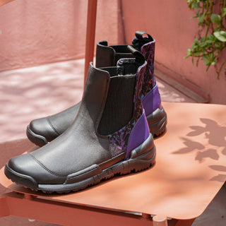 An Inkkas Chelsea boot with a purple textile panel on a coral table, with leaf shadows across it