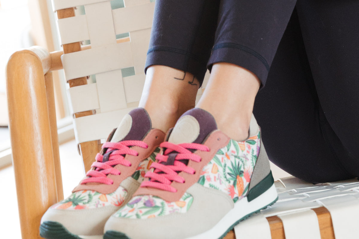 Inkkas Abacaxi joggers with a pink and floral design, worn on a woven chair in bright daylight