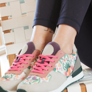 Inkkas Abacaxi joggers with a pink and floral design, worn on a woven chair in bright daylight