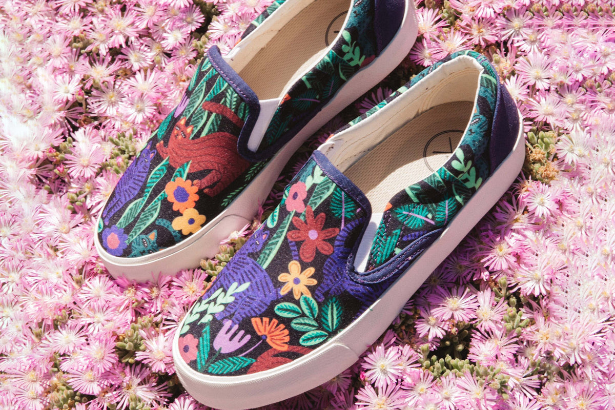 A pair of Inkkas Sokoke Slip Ons resting on a dense bed of pink flowers