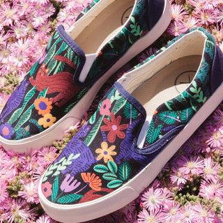 A pair of Inkkas Sokoke Slip Ons resting on a dense bed of pink flowers