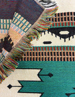 Close-up of a patterned fabric with geometric designs and fringes.