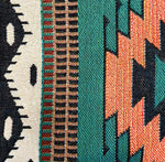Close-up of a woven fabric with geometric patterns in black, white, green, and orange.