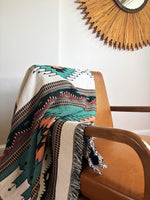 Patterned blanket draped over a chair with a decorative mirror in the background