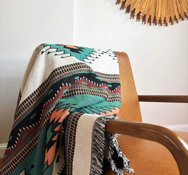 Patterned blanket draped over a chair with a decorative mirror in the background