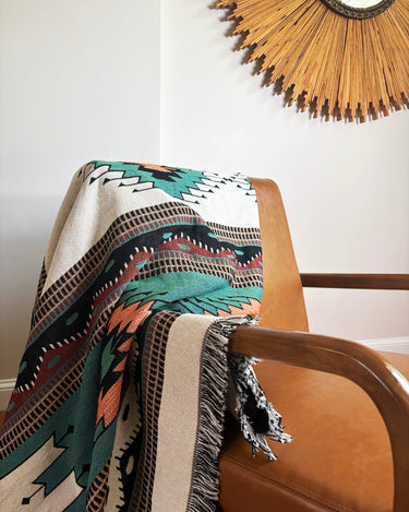 Patterned blanket draped over a chair with a decorative mirror in the background