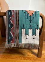 Woven blanket with geometric pattern draped over a wooden chair.