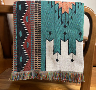 Woven blanket with geometric pattern draped over a wooden chair.