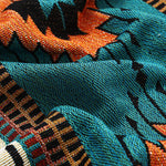 Close-up of a fabric with a pattern of orange, black, and teal colors.