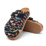 A pair of clog-style mules with a dark navy blue fabric upper covered in a colorful butterfly and caterpillar print, featuring adjustable straps and a brown cork-look sole, shown on a white background.
