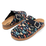 A pair of clogs with a navy blue fabric upper covered in a colorful butterfly print, featuring a wide strap with a gold-tone buckle and a cork-look midsole.