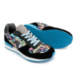 A pair of cushy Joggers shown on a white background, with one shoe standing upright and the other lying on its side to display the sole. The uppers feature a black suede base with a colorful tropical floral and tiger print panel, light blue laces, and a bright blue outsole.