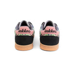 A pair of Inkkas low-top sneakers shown from the back, featuring a black suede heel, pink heel tab with black script logo, and a colorful tropical floral pattern on the sides, finished with a tan rubber sole.