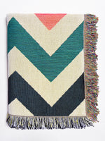 Woven blanket with chevron pattern and colorful fringe on a white background