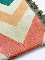 Close-up of a colorful geometric-patterned rug with chevron design on a white background.