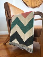 Chevron patterned blanket draped over a wooden chair with a neutral background