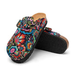 A pair of clog-style mule shoes with a black background covered in a vivid multicolor floral print, featuring a cork-look midsole and black outsole.